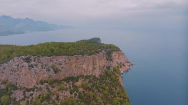 Doğa manzarası. Mavi körfezdeki bir kumsalın insansız hava aracı görüntüsü. Rocky Sahili. Kayalıklardaki yeşil ağaçlar. Yüksek kalite 4k görüntü
