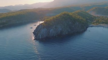 Gün batımında koy. Sahilde yoğun bir orman var. Su nakliyesi yüzüyor. Hafif sis. Hava aracı video görüntüleri. Yüksek kalite 4k görüntü