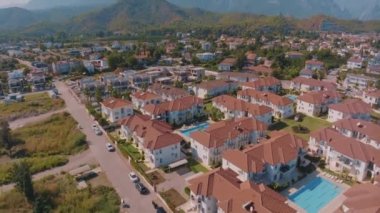 Küçük bir tatil köyünün manzarası. Oteller, evler ve yollar. Çevredeki yeşil tepeler. Çatı katları. Panorama. Hava aracı görüntüleri. Yüksek kalite 4k görüntü