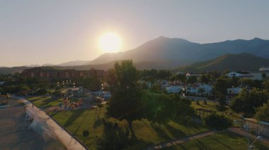Gün batımında otelin hava aracı görüntüsü. Avuçlar. Arka planda dağ manzarası var. Güzel manzara. Yüksek kalite fotoğraf