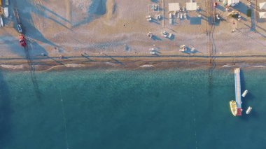 Kıyı şeridinin en üst manzarası. Deniz ve kumlu sahil. Güneşli bir gün. Denizde iskele. Kumsaldaki güneş pansiyonları ve şemsiyeler. Yüksek kalite fotoğraf