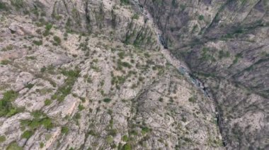 Engebeli kayalık bir kanyonun havadan görünüşü seyrek bitki örtüsü ve içinden akan dar bir nehir.