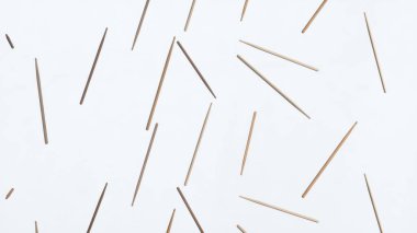 Beyaz bir yüzeyde rastgele dizilmiş sayısız tahta çubuk farklı yönleri gösteren rastgele bir desen oluşturuyor.