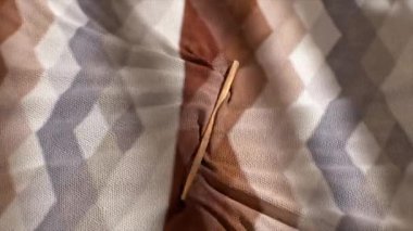 Geometrik desenlere sahip renkli, desenli bir kumaşa yakın çekim, ahşap bir aletle kumaşın bir kıvrımına yerleştirilmiş..