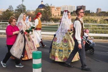 Valencia, Spain - March 17, 2024: People in traditional costumes are going to offer flowers to Our Lady Of The Forsaken In Valencia, Spain clipart