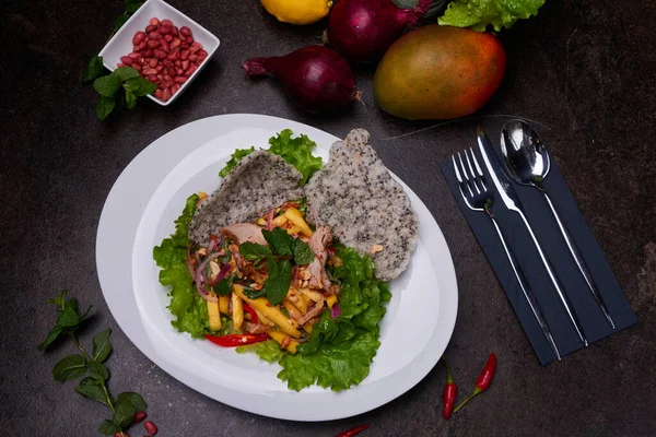 Ördek ve mango salatası. Pan-Asya tabak takımını karanlık masaya koyun. Yüksek kaliteli fotoğraf.