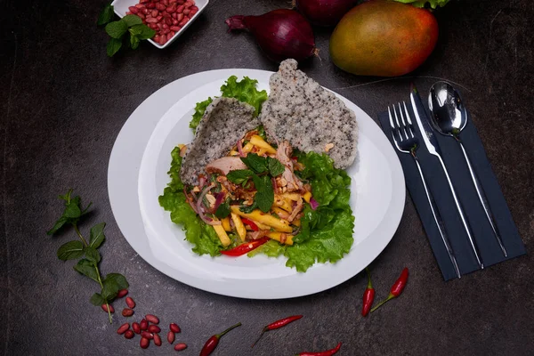 Mangolu ördek salatası. Pan-Asya yemeği, tabağın üstünde, karanlık bir masanın üstünde. Yüksek kaliteli fotoğraf.