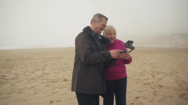 Casal Caucasiano Sênior Atraente Assistindo Filmagens Celular Rindo Praia Homem — Vídeo de Stock