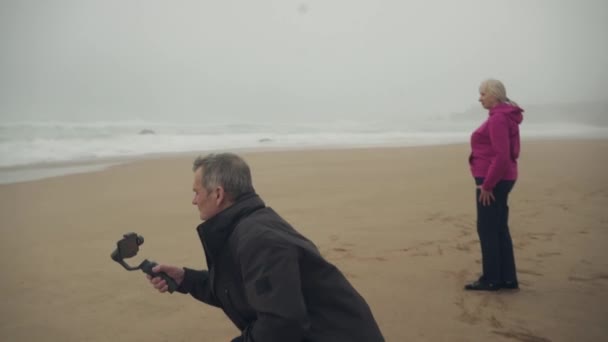 Homem Caucasiano Sênior Filmando Praia Usando Gimbal Telefone Uma Mulher — Vídeo de Stock