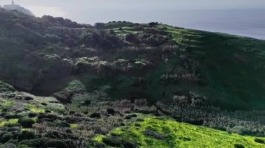 Portekiz Cabo da Roca 'daki yeşil uçurumların üzerinde uçan hava manzarası. Yatay video
