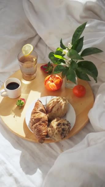 阳光明媚的早晨 早餐放在床上的木制盘子里 上面铺着白色的亚麻布 垂直的4K镜头 转来转去 — 图库视频影像