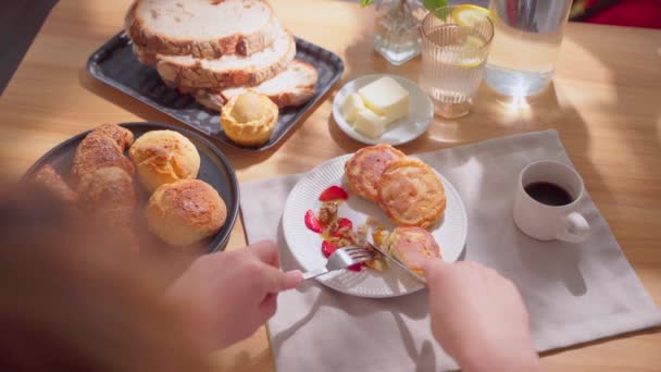 화창한 테이블에 유럽식 식사의 팬케이크를 자르는 여자의 클로즈업 고품질 — 비디오