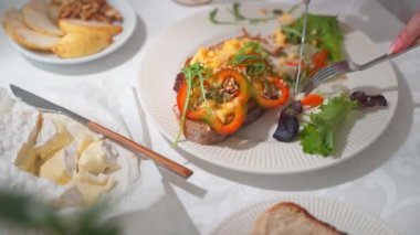 Çırpılmış yumurta ve sebze turşusuyla tost yemeye yakın çekim. Masa örtüsü ve yemek takımı olan bir masa. Yüksek kalite 4K görüntü