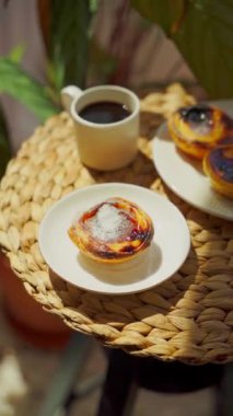 Pastel de nata ve kahve yuvarlak bir sehpada güneşli bir günde. Üst görünüm dikey video. Yüksek kalite 4k görüntü