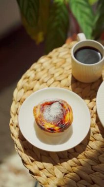 Pastel de nata ve kahve yuvarlak bir sehpada güneşli bir günde. Üst görünüm dikey video. Yüksek kalite 4k görüntü
