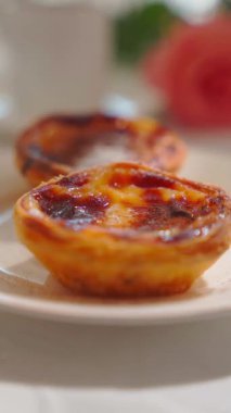 Pastel de nata, güneşli bir günde beyaz bir tabakta. Yakın çekim dikey video. Yüksek kalite 4k görüntü