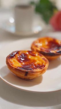  Geleneksel Portekiz tatlı pastel de nata beyaz tabakta. Yüksek kalite 4k görüntü, dikey video, kamera hareketini dikey olarak kaldır.