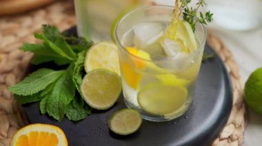 Portakal, limon ve limonla süslenmiş bir masada naneli ve kekikli iki bardak narenciyeli su. Yüksek kalite 4K görüntü. Üst görünüm, eğik hareket