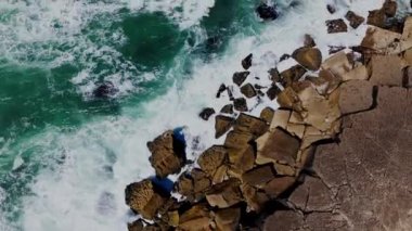 Atlantik Okyanusu 'nun kayalık bir kıyısındaki dalgaların hava görüntüsü. Praia das Macas 'ın kıyı şeridi, Azenhas do Mar, Sintra, Portekiz. Yüksek kalite 4k görüntü