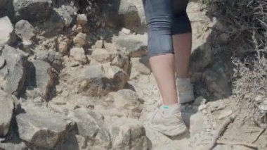 Beyaz kadın, kırmızı tişörtlü, Atlantik kıyısındaki Cascais-Sintra Doğal Parkı boyunca manzaralı uçurumlarda yürüyüş yapıyor. 