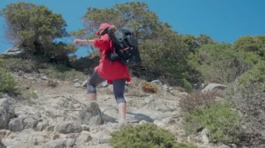 Beyaz kadın, kırmızı tişört ve siyah fotoğraf sırt çantası giymiş Atlantik kıyısı boyunca manzaralı uçurumlarda yürüyüş yapıyor. Portekiz 'in Cascais-Sintra Doğal Parkı' ndaki Ursa Sahili manzaralı. 
