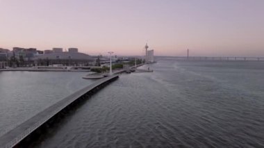 Tagus Nehri ve ikonik Vasco da Gama Köprüsü ile Alacakaranlık Saati boyunca sahil boyunca uzanan teleferiklerin yer aldığı, Lisbons Milletler Parkının parkı das Nacoes 'un hava görüntüsü..