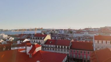 Lizbon şehir merkezinde gün batımında şehrin çatılarını ve Tagus Nehri 'ni çekerken hava görüntüsü alıyorum. Dikey İHA görüntüleri. Yüksek kalite 4k görüntü