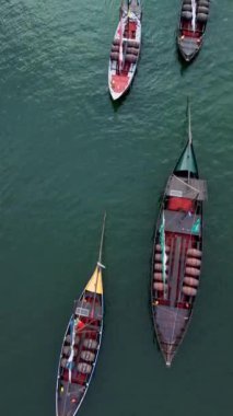 İnsansız hava aracı Porto 'daki Douro Nehri' ndeki geleneksel tahta botların tam üstünde uçuyor. Dikey video 