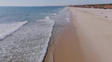 Falesia Sahili üzerinde uçan İHA dalgaları, kumlu kumsallar ve terracotta kayalarını ortaya çıkarıyor. Vilamoura, Algarve. 