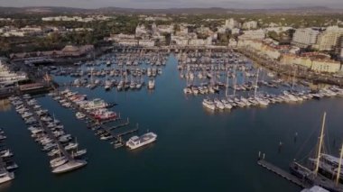 İnsansız hava aracı Vilamoura marinası boyunca uzanırken şehir altın saatinde arka planda olacak. Portekiz 'in güneyinde, Algarve bölgesinde ünlü bir seyahat merkezi.. 