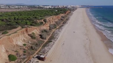 Falesia Sahili üzerinde uçan İHA dalgaları, kumlu kumsallar ve terracotta kayalarını ortaya çıkarıyor. Vilamoura, Algarve. 