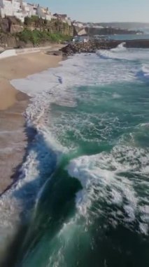 İnsansız hava aracı, Portekiz 'in Ericeira kıyı köyü boyunca uçuyor. Dikey video. Yüksek kalite 4K görüntü