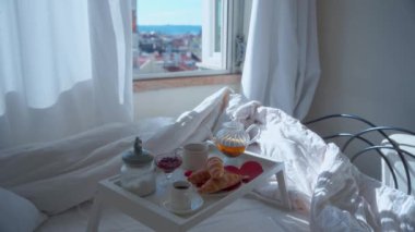 Romantik Sevgililer Günü kahvaltısı, taze pişmiş kruvasan, çay ve reçel içeren yumuşak doğal ışık. Kalp şeklindeki dekorla biçimlendirilmiş