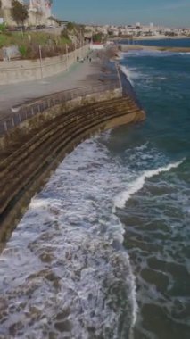 Drone gün batımında Praia do Tamariz sahilinde uçuyor. Estoril, Portekiz