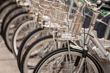 Bisikletleri ve tekerlekleri üzerinde seçici bulanıklık, Avrupa kentsel ortamında bisiklet paylaşımı için kullanılan bir bisiklet istasyonunun kirasına park edilmiş.