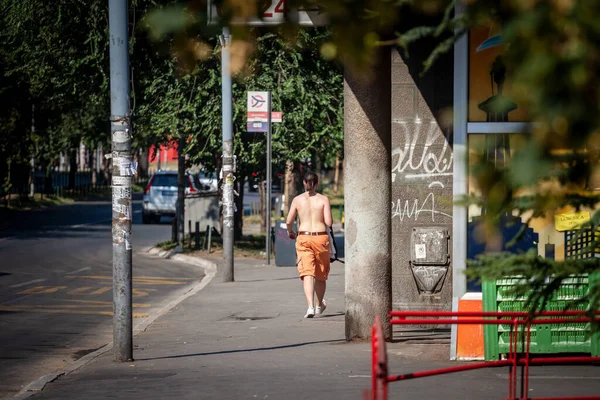 BELGRAD, SERBIA - 23 Temmuz 2022: Orta Avrupa 'da sıcak bir sıcak hava dalgası sırasında, Belgrad' ın ıssız bir caddesinde üstsüz yürüyen bir adamın seçici bulanıklığı