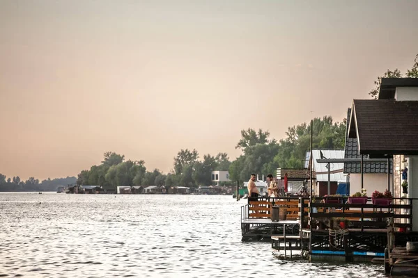 BELGRAD, SERBIA - 31 Temmuz 2021: Obrenovac, Belgrad 'da Reka Sava Nehri' nde bir Sırp sal yüzen evinde, bir çıkıntının üzerinde duran gençler için seçici bulanıklık