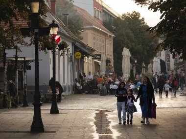 BELGRADE, SERBIA - SEPTEMBER 24, 2024: Selective blur on a Serbian family, a mother and her kids, walking by the Gospodska ulica street, the main street of Zemun
