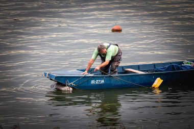 BELGRADE, SERBIA - SEPTEMBER 25, 2022: Selective blur on a man, Fisherman preparing to go fishing on the Danube river standing on his small boat on Zemunski kej, in Zemun, a northern district of Belgrade
