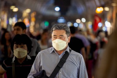 ISTANBUL, TURKEY - MAY 21, 2022: Selective blur on an old man, asian, senior, walking in kapalicarsi grand bazaar, wearing a face mask in a crowd during the Covid 19 Coronavirus pandemic