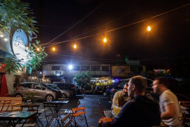 BELGRADE, SERBIA - JUNE 25, 2022: Selective blur on Blurry young serbian men sitting at the terrace of a cafe and bar of Cetinjska, an alternative former factory reconverted into bars and clubs in the city center of Belgrade. 