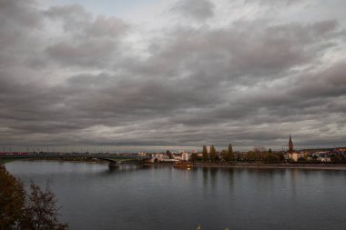 Alacakaranlıkta, Bonn 'daki Ren Nehri' nin panoraması Kennedy Köprüsü 'nün önünde. Bonn, Almanya 'nın Nordrhein Westfalen eyaletinde yer alan bir şehirdir..