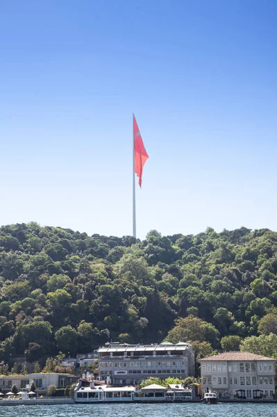 Giant turkish flag waiving on a flagpole above Luxury houses on the Bosphorus strait in Istanbul, Turkey, in a residential district of the city, by the marmara sea, in a high real estate development area.