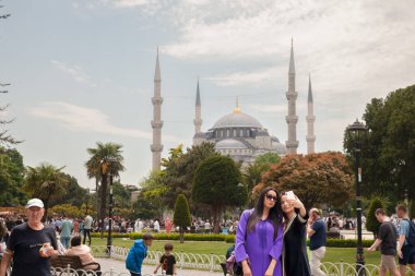 ISTANBUL, TURKEY - 22 Mayıs 2022: İki kadın, kız, turist Sultanahmet Camii 'nin önünde akıllı telefonuyla selfie çeken Mavi Cami adlı Müslüman bir ibadethane, Osmanlı mimarisinin sembolü.