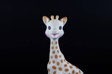 PARIS, FRANCE - 1 Mart 2023: siyah arka planda Zürafa Sophie 'nin kafasına yakın planda seçici bulanıklık. Sophie la Girafe, Vulli tarafından Fransa 'da üretilen, bebekler için diş çıkarmada kullanılan bir oyuncak..
