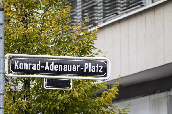 ドイツの元キリスト教民主主義首相コンラート アデナウアーに捧げデュッセルドルフ市内中心部の主要な広場の一つであるコンラート アデナウアー プラッツ広場を示す道路標識上の選択的なぼやけ — ストック写真