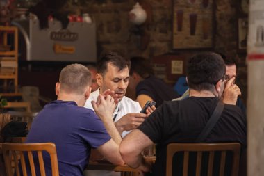 İSTANBUL, TURKEY - 20 Mayıs 2022: İstanbul 'da bir restoranda akşam vakti Türklere yönelik seçici bulanıklık, kimileri yemek yiyor, kimileri akıllı telefonu telefonla internette gezinmek için kullanıyor.
