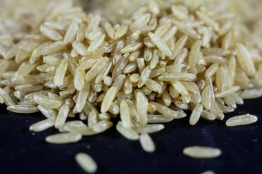 Esmer pirinç yığınının stüdyo makro çekimi, ayrıca tam, integral veya tam tahıllı pirinç olarak da adlandırılır, bulanık bir arka planı vardır. Esmer pirinç lif bakımından zengindir ve çeşitli diyetlerde kullanılır..