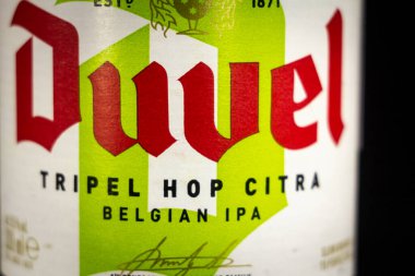 LIEGE, BELGIUM - 21 Nisan 2023: Bir şişe Duvel Tripel Hop Citra bira etiketinde seçici bulanıklık. Duvel, Flanders 'taki Moorgat bira fabrikası tarafından üretilen Belçika birasıdır..
