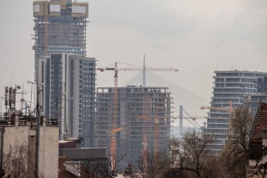 Bir emlak geliştirme alanında inşaat iskeleleri, beton ve beton cepheleri ve vinçleri olan gökdelen kulelerinden oluşan bir bina kompleksinin panoraması..
